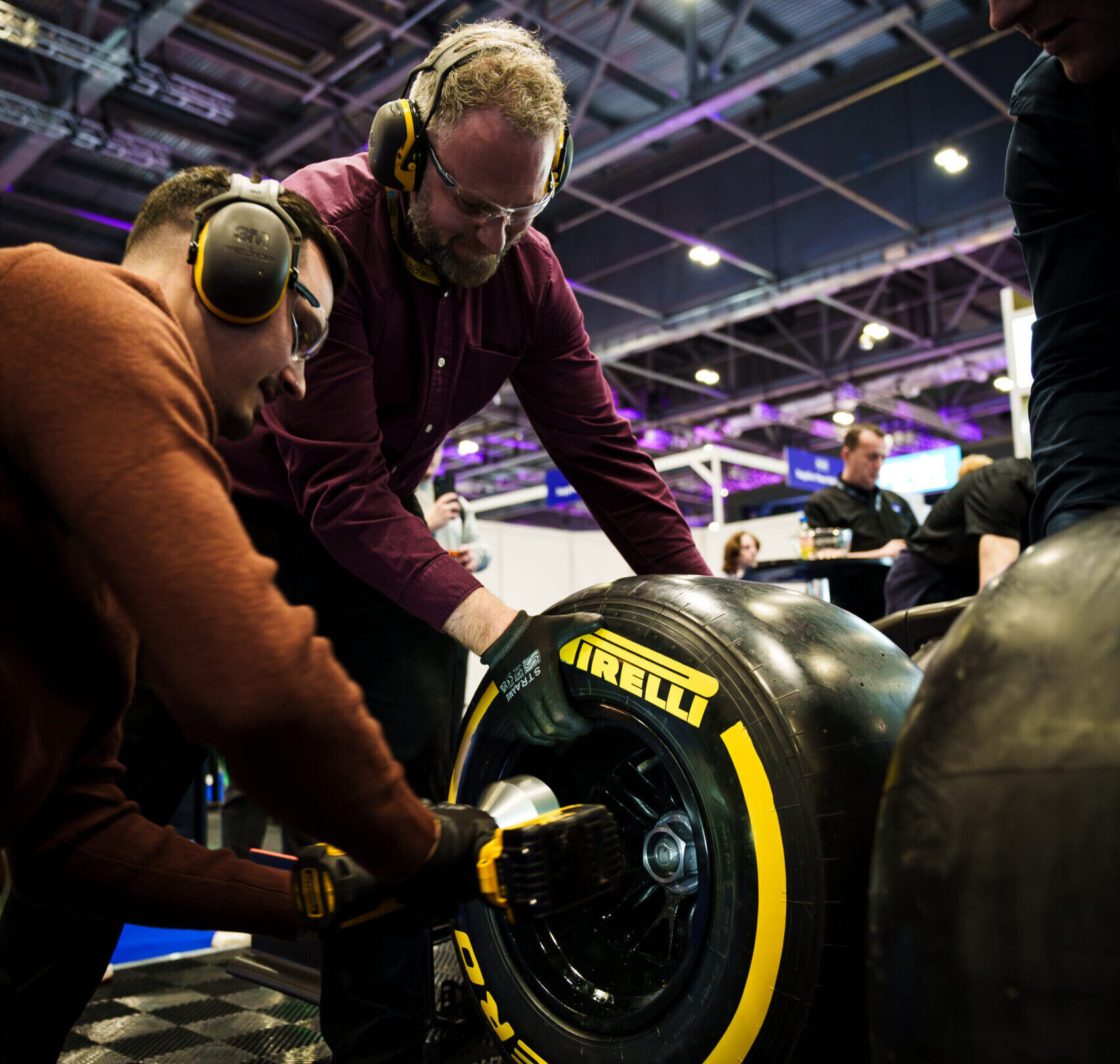 Pit stop challenge team changing tyres on replica racing car during corporate away day